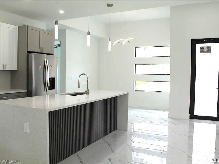 Modern kitchen with a large island featuring a waterfall countertop and a fluted wood-finish panel