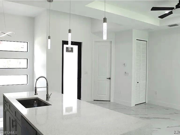 Spacious kitchen island featuring a light-toned countertop, integrated sink, and modern pull-down faucet
