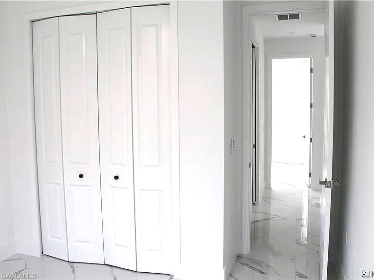 White bi-fold closet doors with black hardware, complementing the polished stone-look flooring