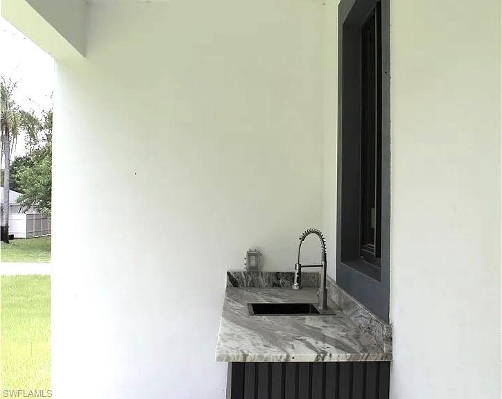 Outdoor kitchen area featuring a dark stone countertop, black undermount sink, and a high-arc pull-down faucet