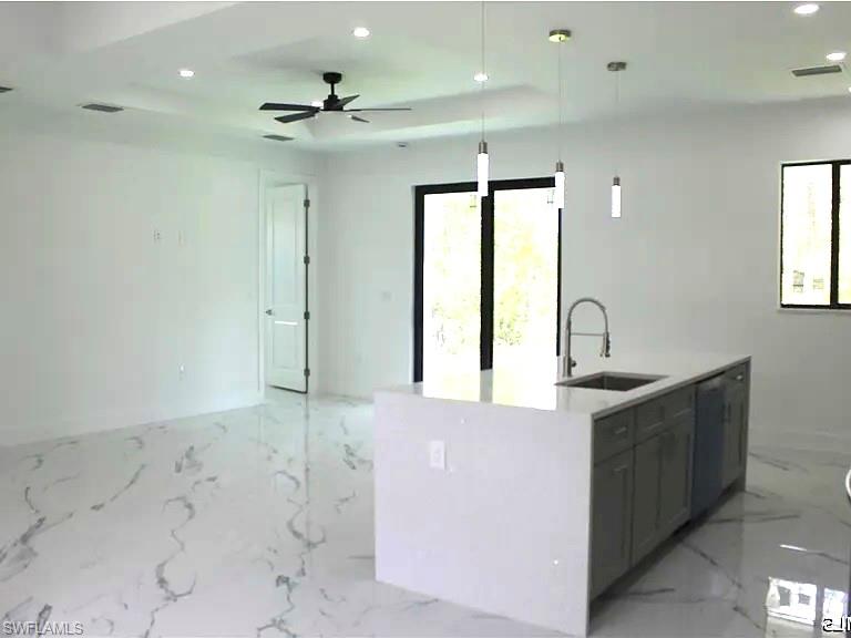 Open-concept living space featuring a kitchen island with integrated sink, pendant lighting, contemporary ceiling fan, recessed lighting, and large format marble-look flooring