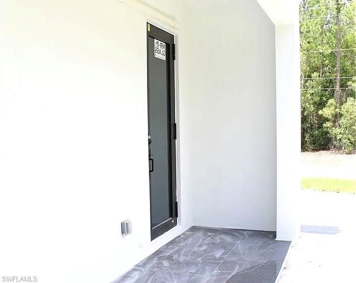 Black-framed glass entry door with a privacy film, set within a white stucco exterior