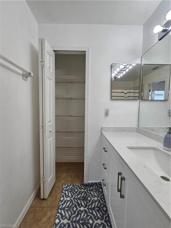 Bathroom featuring a vanity with a white countertop and integrated sink, white cabinetry with metal pulls, and a wall-mounted mirror
