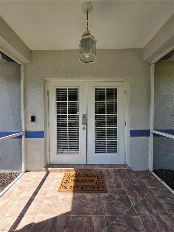 Double entry doors with integrated blinds, hexagonal pendant light fixture, screen enclosure, and a tiled porch surface