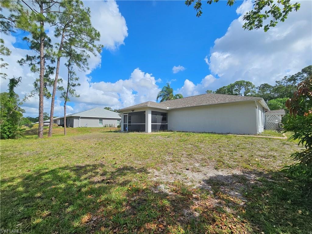 Expansive rear yard featuring mature pine trees, a screened lanai, and a neutral-toned exterior