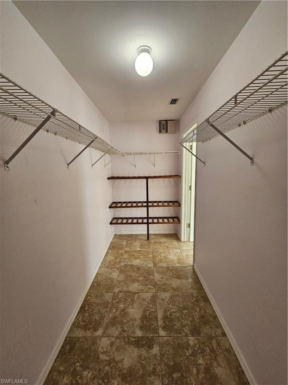 Spacious closet featuring tiled flooring, built-in wire shelving, and additional shelving units