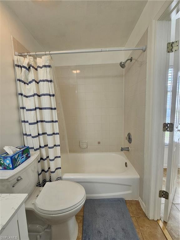 Full bathroom featuring a white bathtub with a tiled shower surround, a white toilet, and a vanity with a white countertop