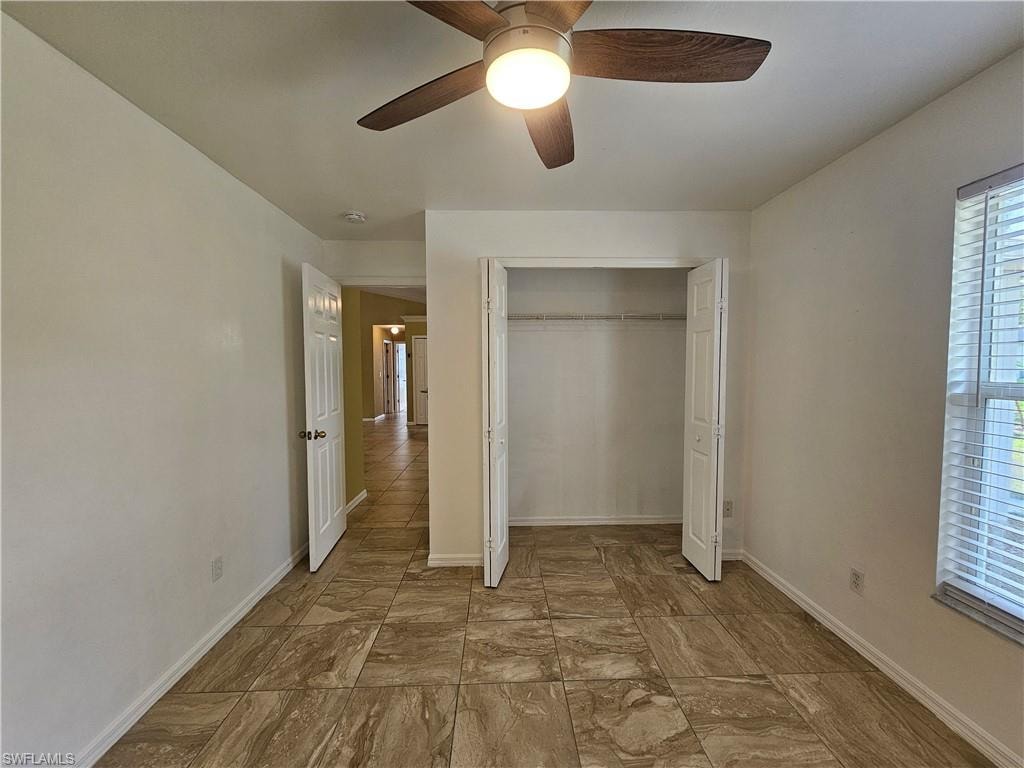 Room featuring tile flooring, a ceiling fan with light fixture, a window with horizontal blinds, and a bi-fold door closet