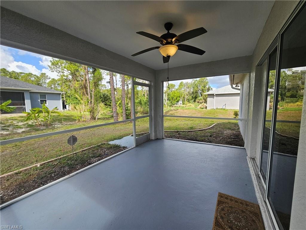 Screened patio featuring a ceiling fan, painted concrete flooring, and sliding glass door access to the interior