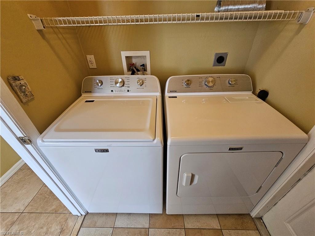 Dedicated laundry area featuring a washer and dryer set, wire shelving, and tiled flooring