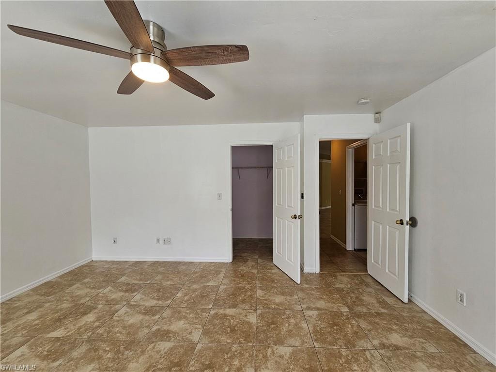 Spacious room featuring tile flooring, a contemporary ceiling fan with integrated lighting, multiple doorways, and crisp white walls