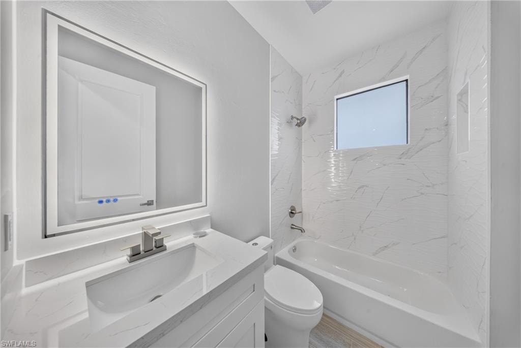 Contemporary bathroom featuring a sleek vanity with an integrated sink, a backlit mirror, and a full-size bathtub