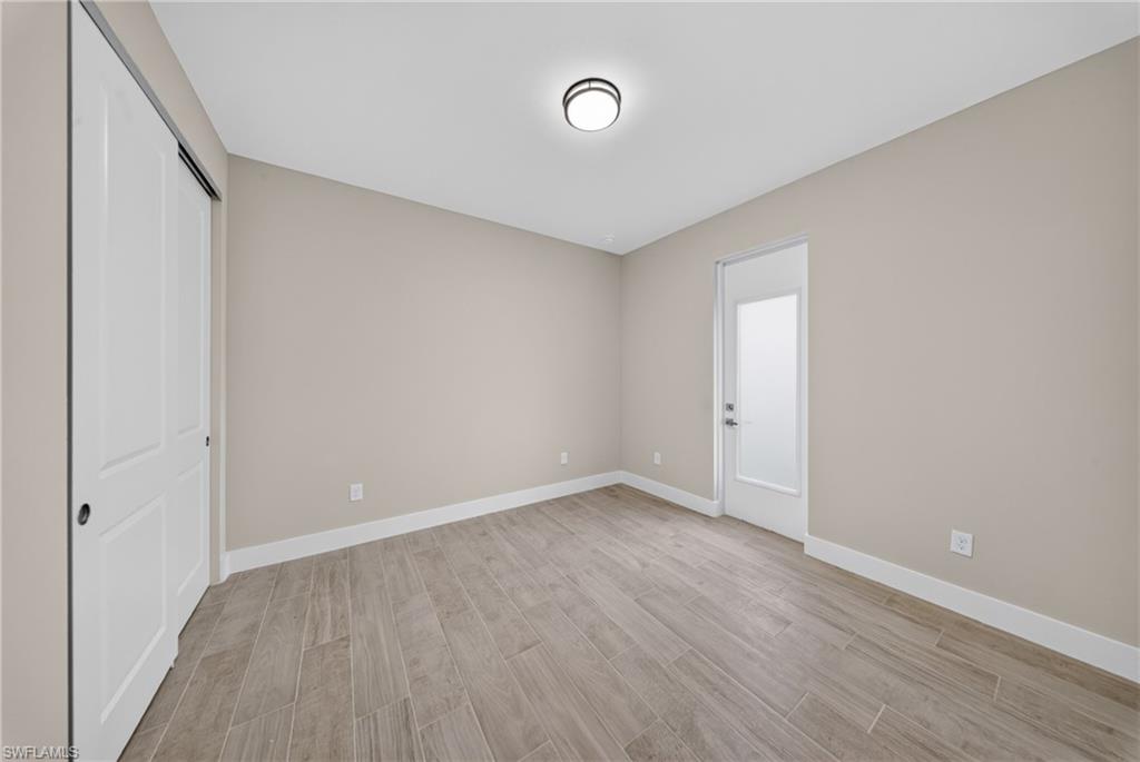 Neutral tone walls with white baseboards frame wood-look tile flooring
