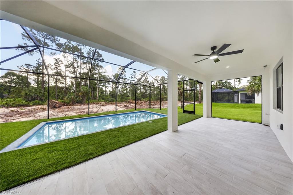 Expansive screened lanai featuring a rectangular pool and artificial turf surround