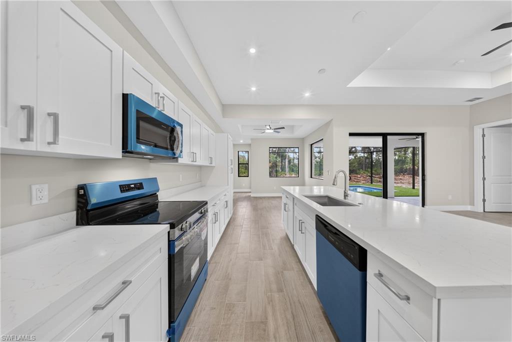 Contemporary kitchen featuring white cabinetry, light-toned countertops, and blue-accented appliances