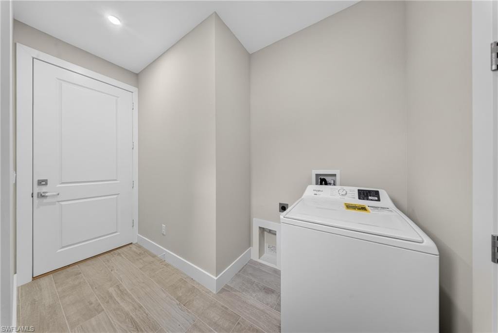 Laundry area featuring a top-load washing machine, light neutral wall paint, recessed ceiling lighting, and wood-finish tile flooring
