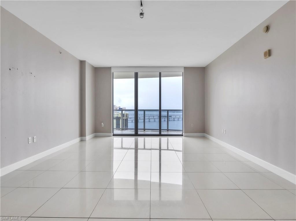 Spare room with a wall of windows and light tile patterned floors