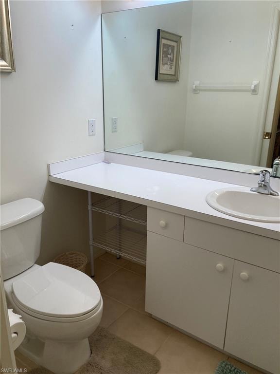 Half bath featuring toilet, vanity, and tile patterned flooring