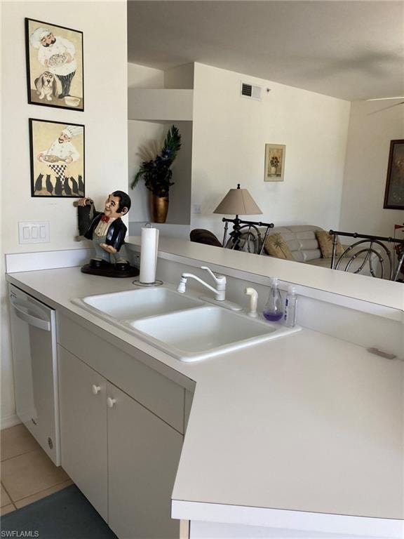 Kitchen featuring stainless steel dishwasher, a sink, light countertops, and light tile patterned floors