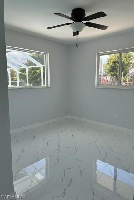 Spacious room featuring high-gloss tile flooring with a marble-effect pattern, white baseboards, and light gray painted walls