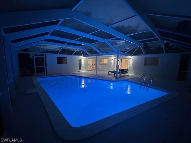 Screened-in pool enclosure featuring a rectangular swimming pool with integrated lighting