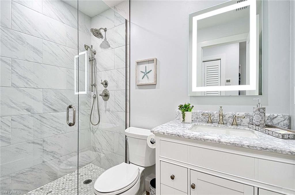 Bathroom featuring a shower with shower door, oversized vanity, and toilet