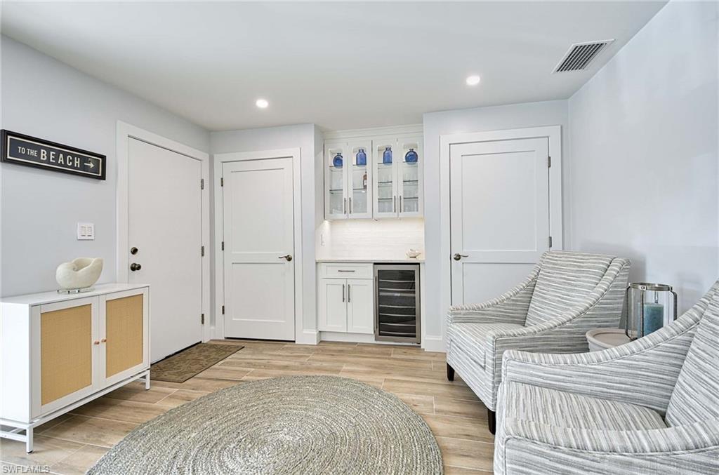 Living area with beverage cooler and light wood-type flooring