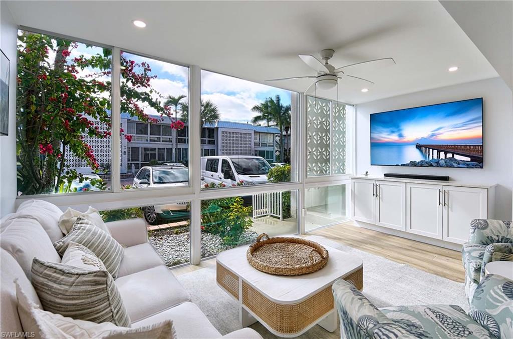 Living room with ceiling fan, light hardwood / wood-style flooring, and floor to ceiling windows