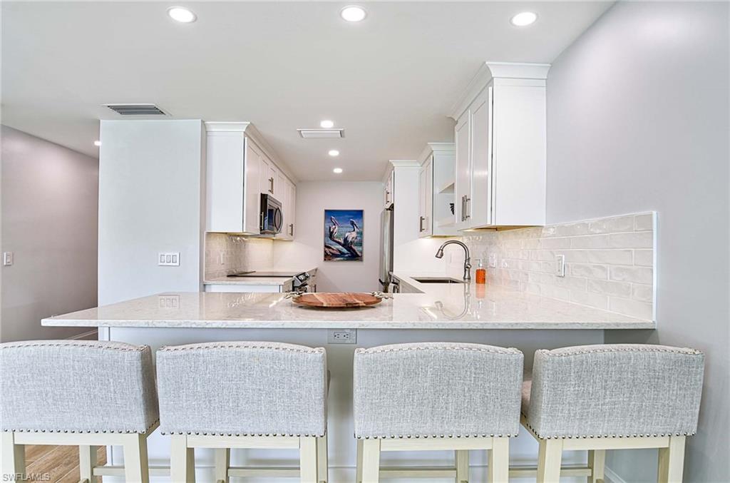 Kitchen featuring sink, backsplash, a breakfast bar area, and kitchen peninsula