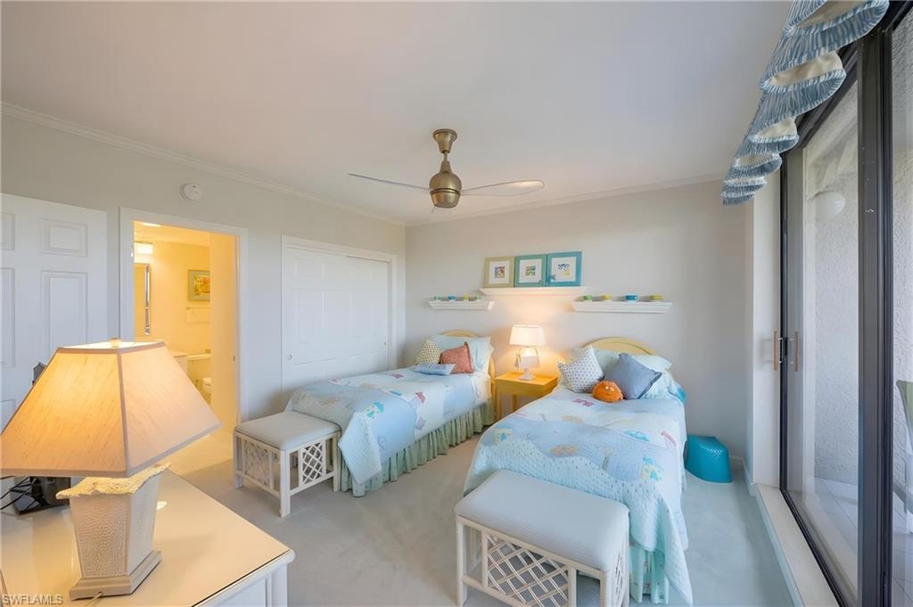 Bedroom with private balcony access, ceiling fan, and light-colored carpeting
