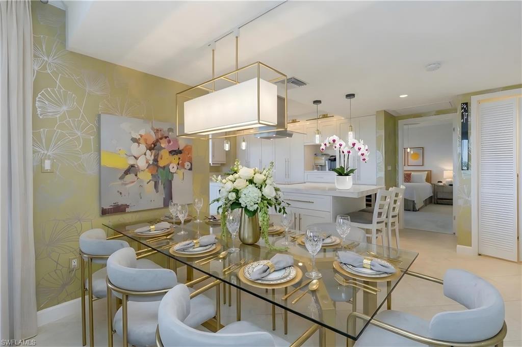 Open-concept dining area with a glass-top table, gold-finished chairs, and a rectangular pendant light fixture