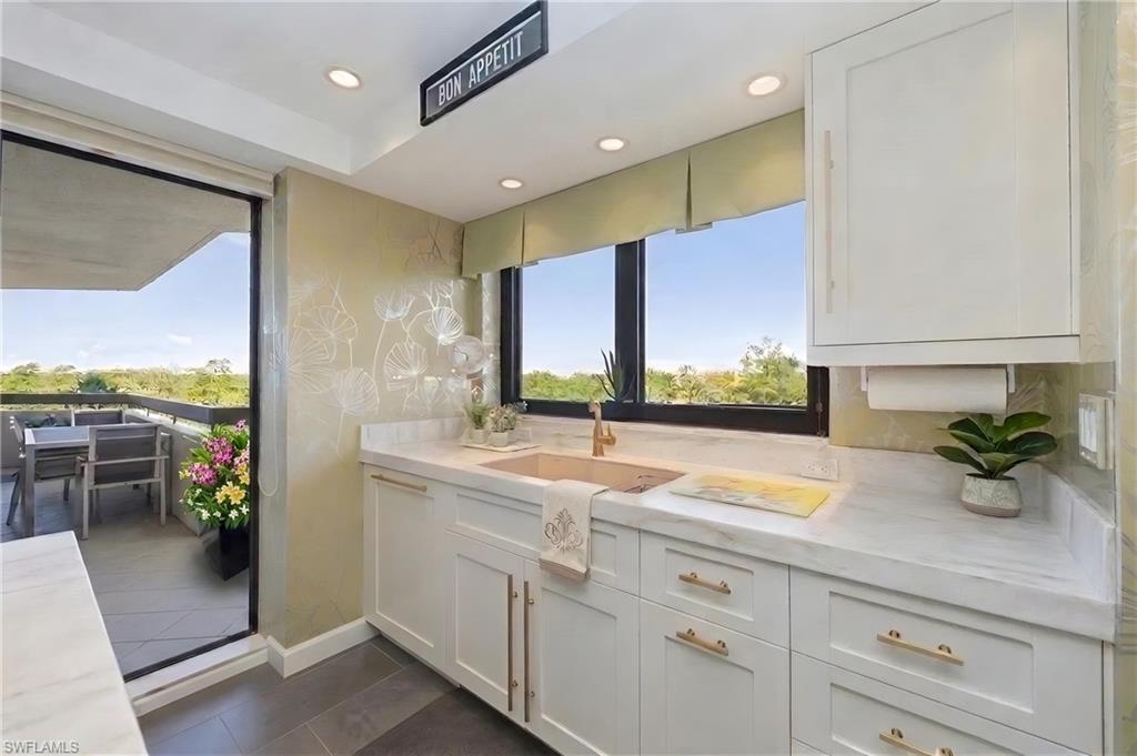 Kitchenette with white shaker cabinetry, white countertops, and gold-finish hardware