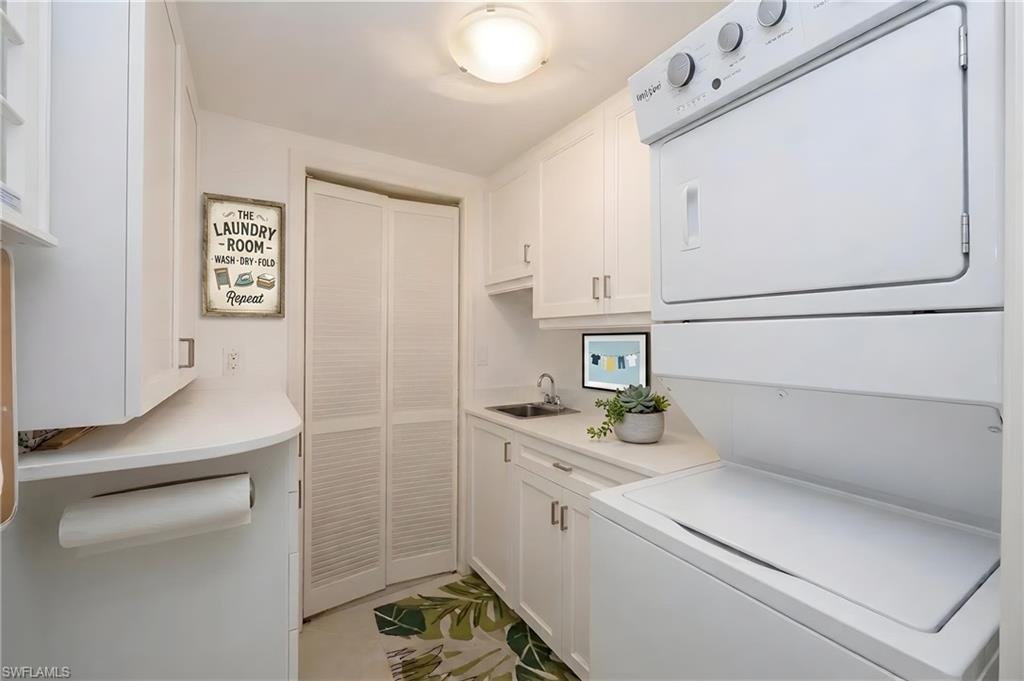 Dedicated laundry area featuring a stacked washer and dryer unit, ample white cabinetry, a utility sink, and white countertops
