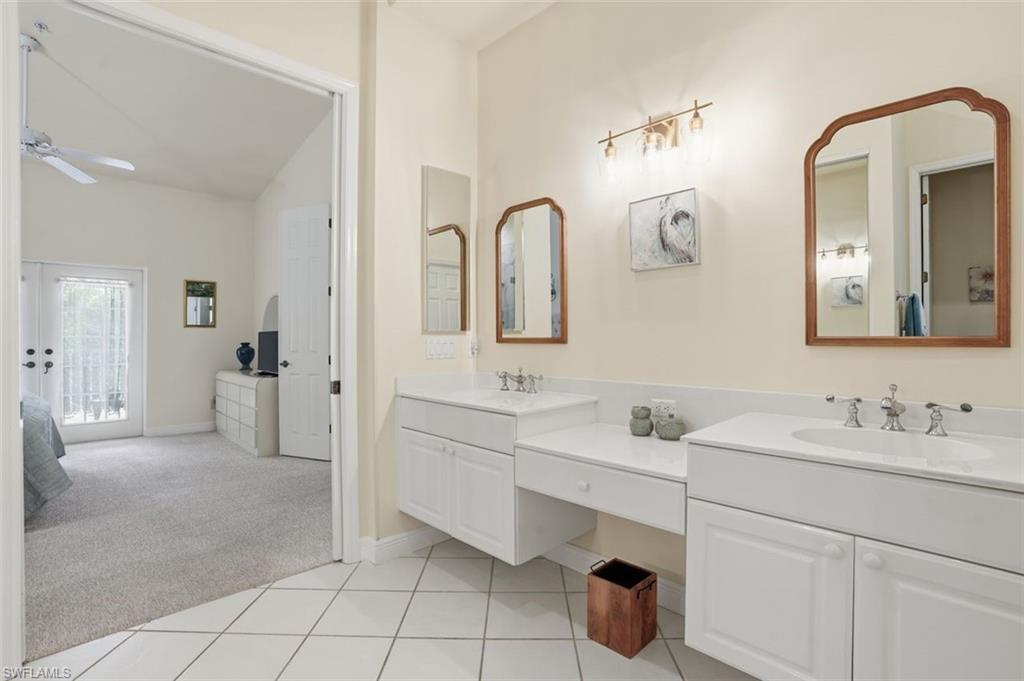 Bathroom featuring dual vanities with white cabinetry and integrated sinks, white countertops, and wall-mounted mirrors