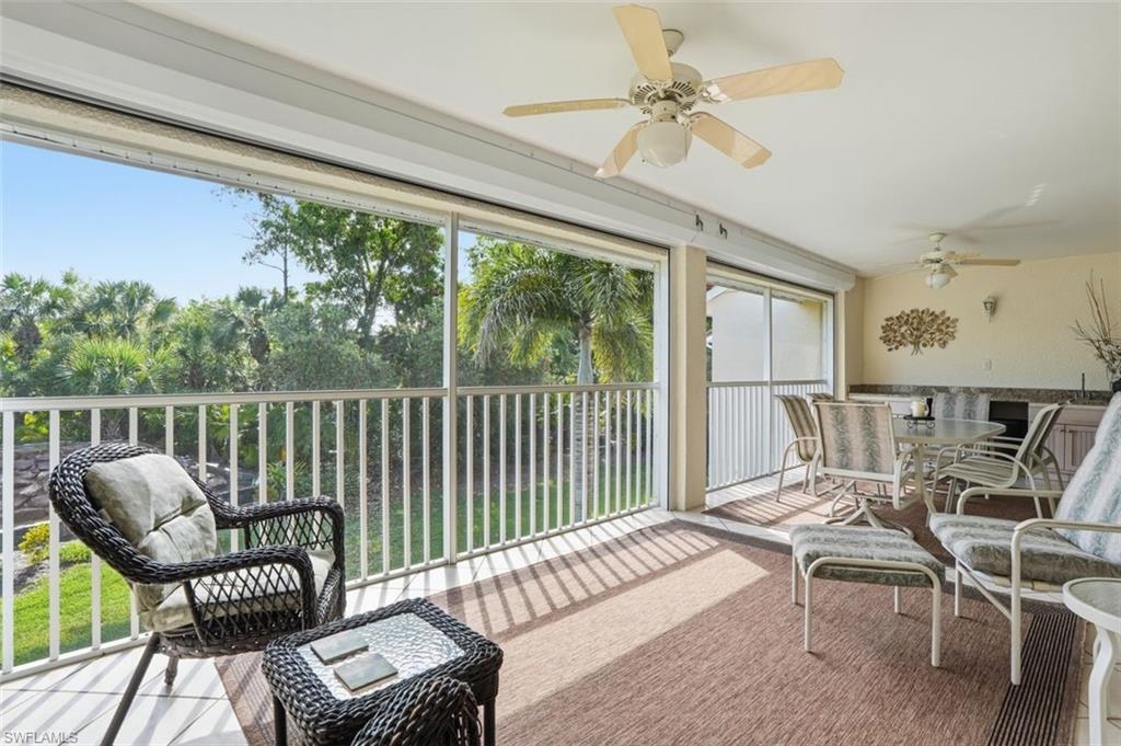 Screened lanai featuring multiple ceiling fans, built-in countertops, cabinets and refrigerator for outdoor entertaining