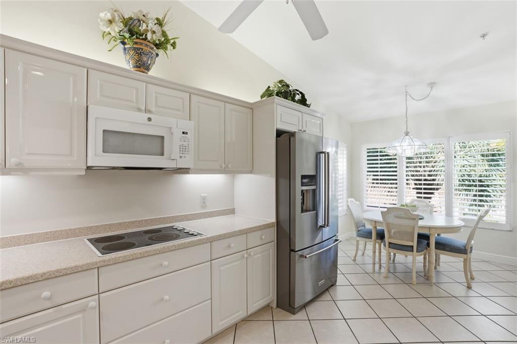 Kitchen with light cabinetry, built-in microwave, integrated cooktop, and stainless steel refrigerator
