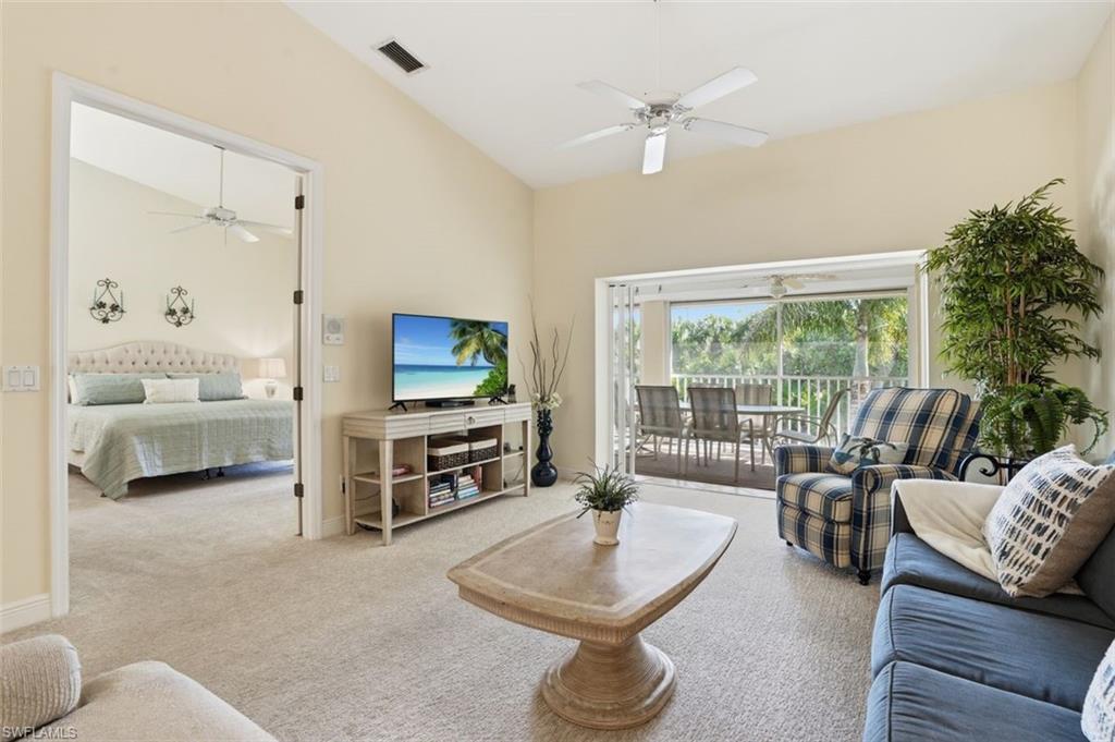 Spacious living area with vaulted ceilings, a ceiling fan, and access to an outdoor screened lanai