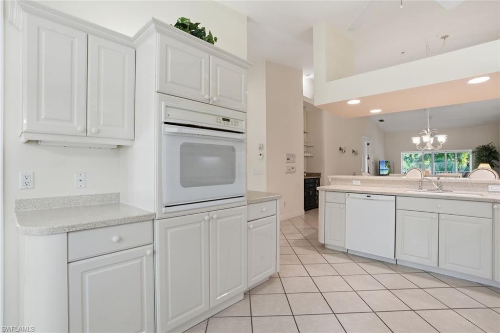 Kitchen featuring white cabinetry, light-toned countertops, a built-in oven, and a dishwasher