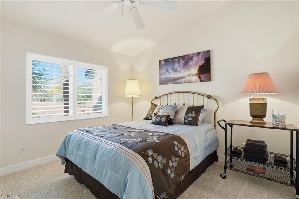 Bedroom featuring dual windows with plantation shutters and a ceiling fan