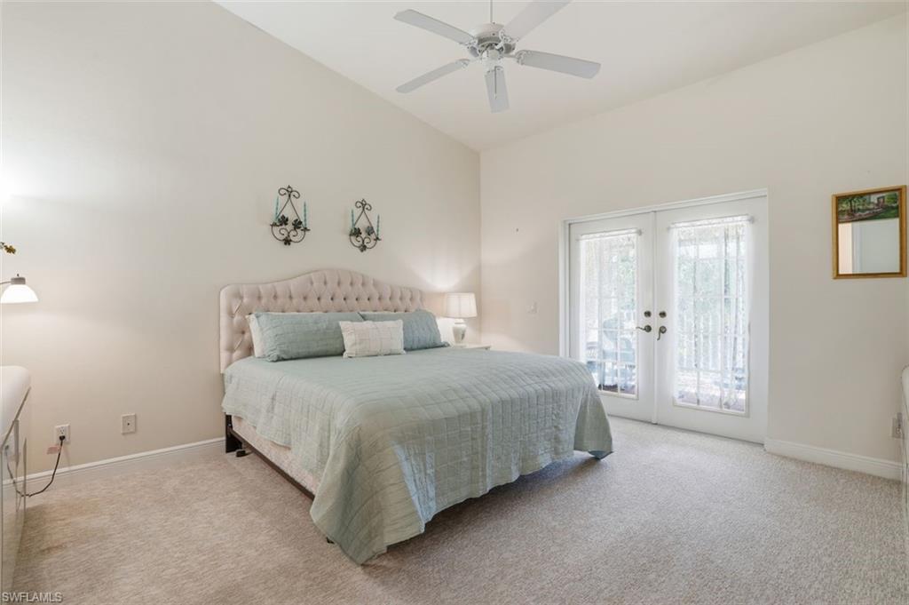 Vaulted ceilings featuring a ceiling fan, plush carpeting, double French doors, and soft neutral wall tones