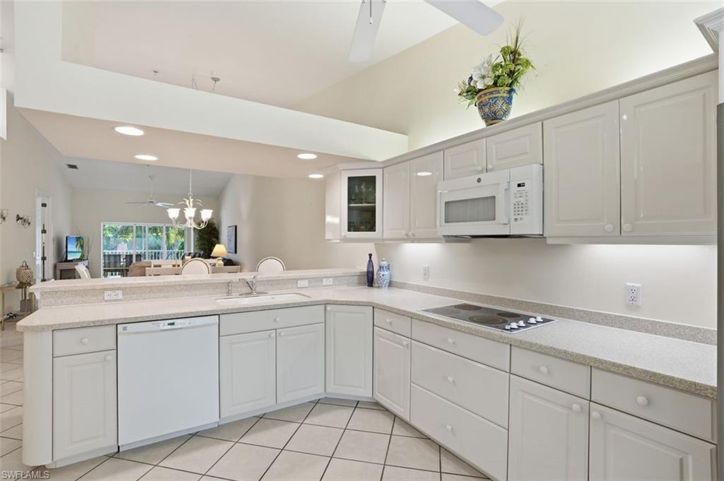 Kitchen featuring white cabinetry, light-toned countertops, a built-in microwave, and an electric cooktop