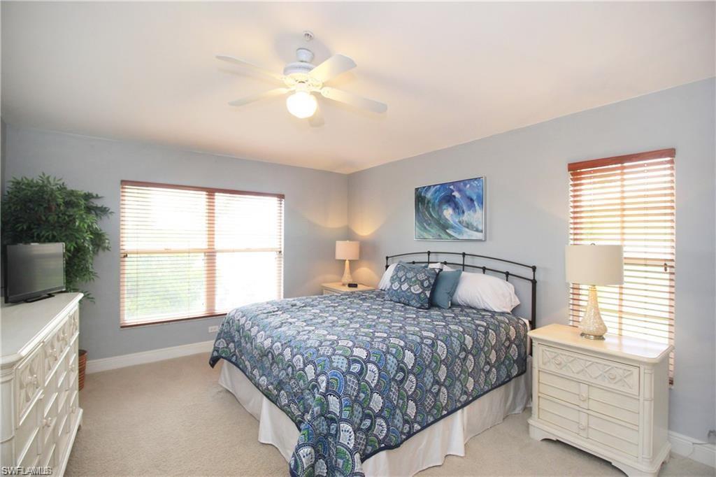 Carpeted bedroom with multiple windows and ceiling fan