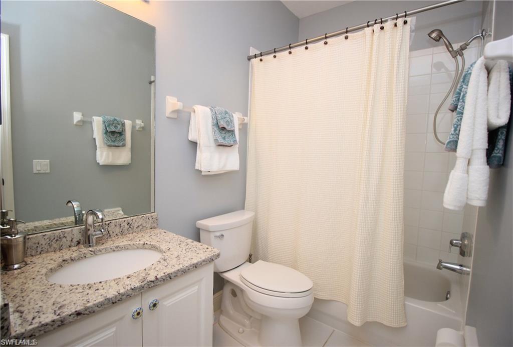 Full bathroom featuring tile patterned flooring, vanity, toilet, and shower / bath combo with shower curtain