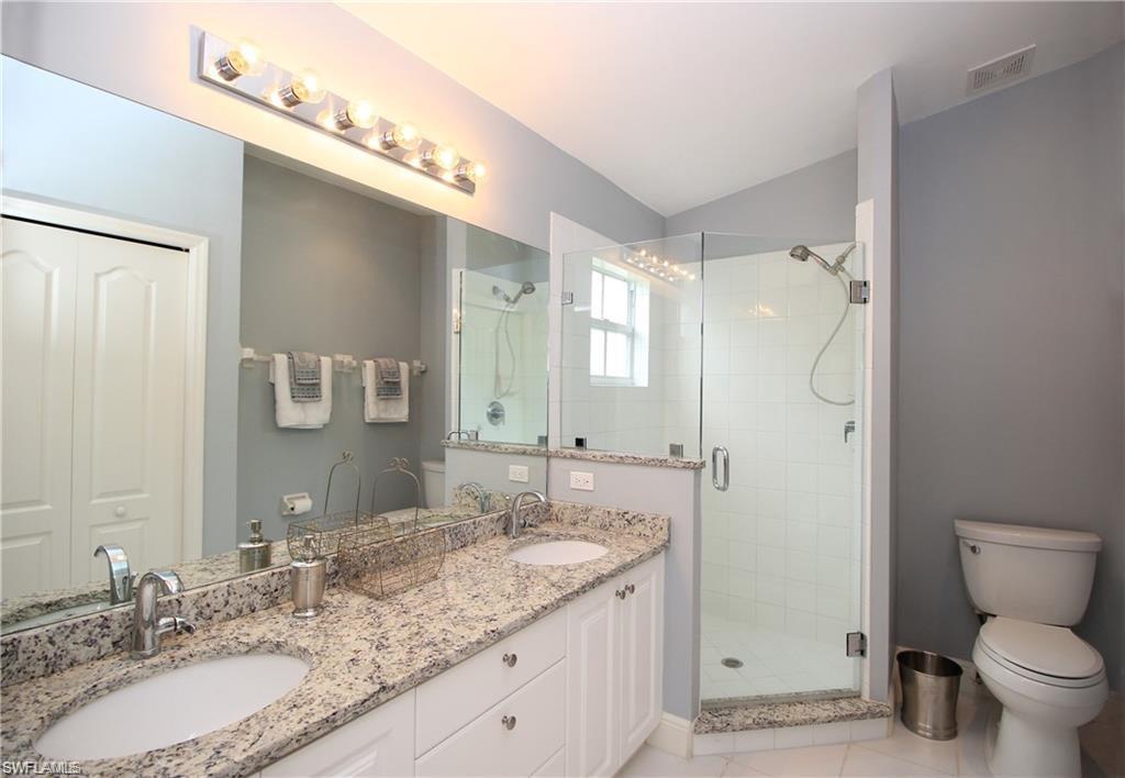 Bathroom with vanity, toilet, tile patterned floors, and a shower with door