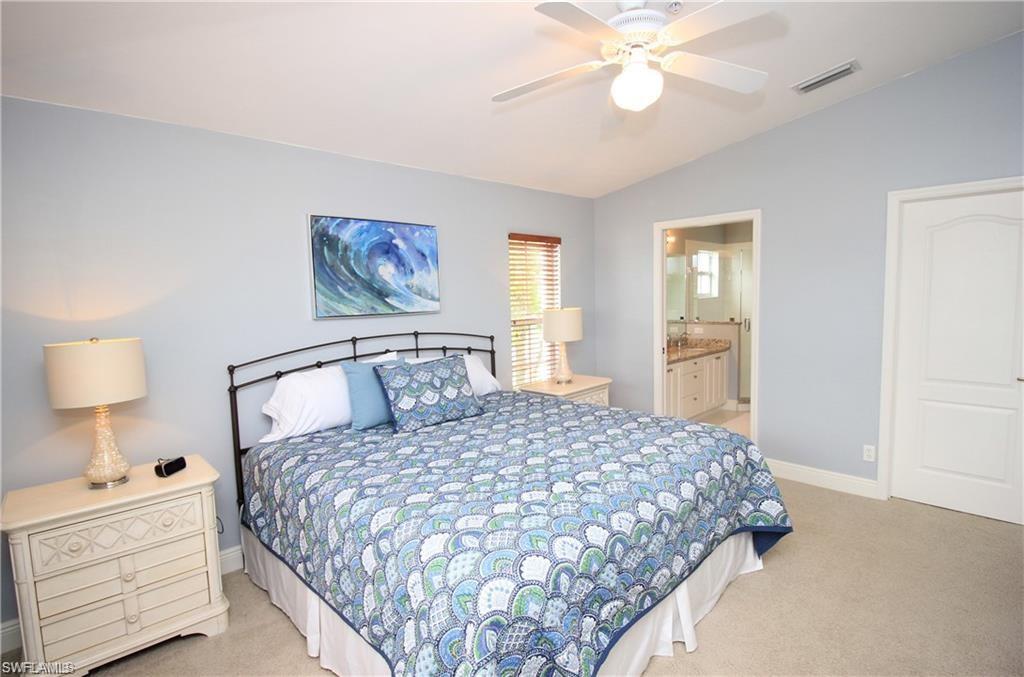 Carpeted bedroom with lofted ceiling, connected bathroom, and ceiling fan