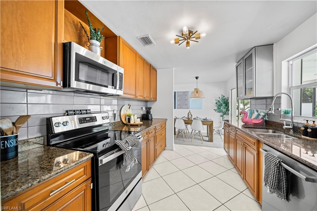 Kitchen featuring wood-finish cabinetry, stainless steel appliances, granite-style countertops, and a tile backsplash