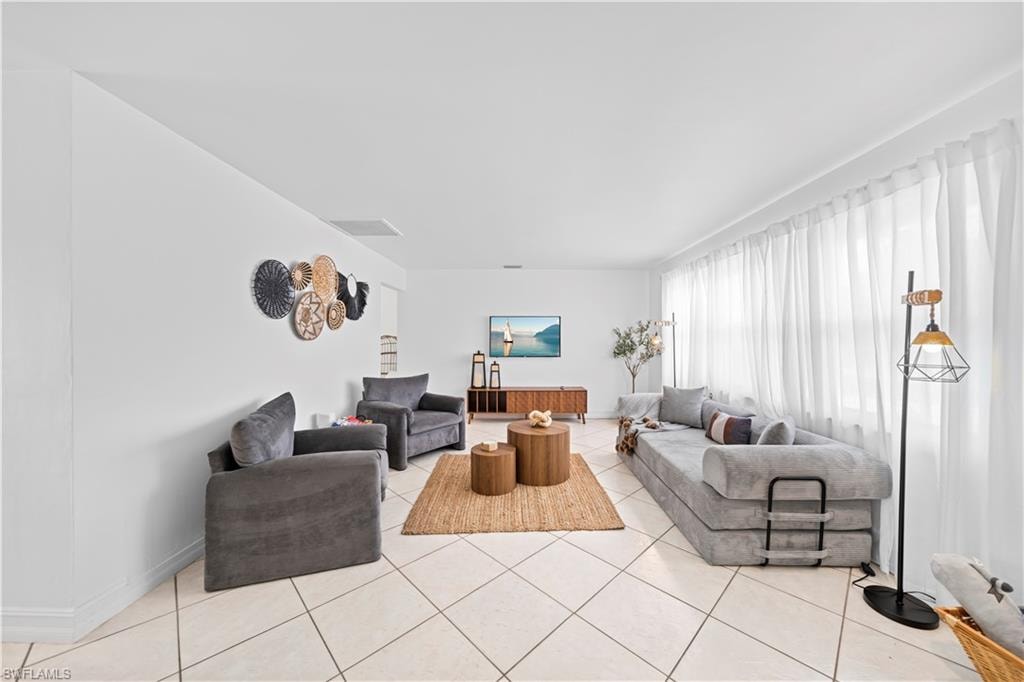 Living area featuring diagonal tile flooring, white walls, and a full wall of sheer white window treatments
