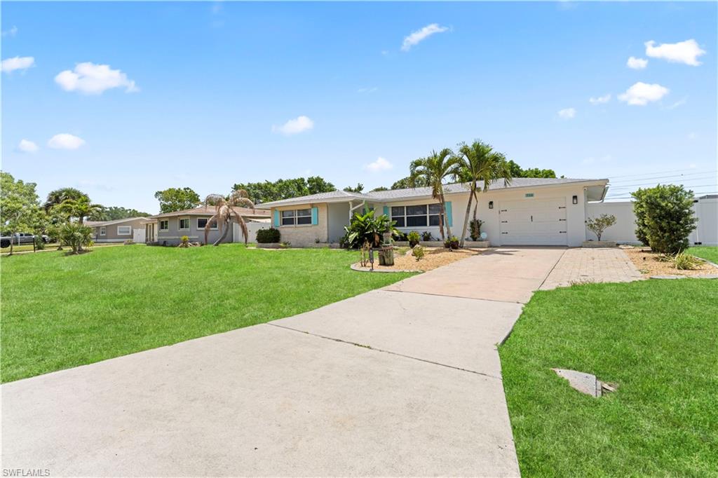 Single-story residence featuring a white exterior, attached garage, concrete driveway, and a brick paver section