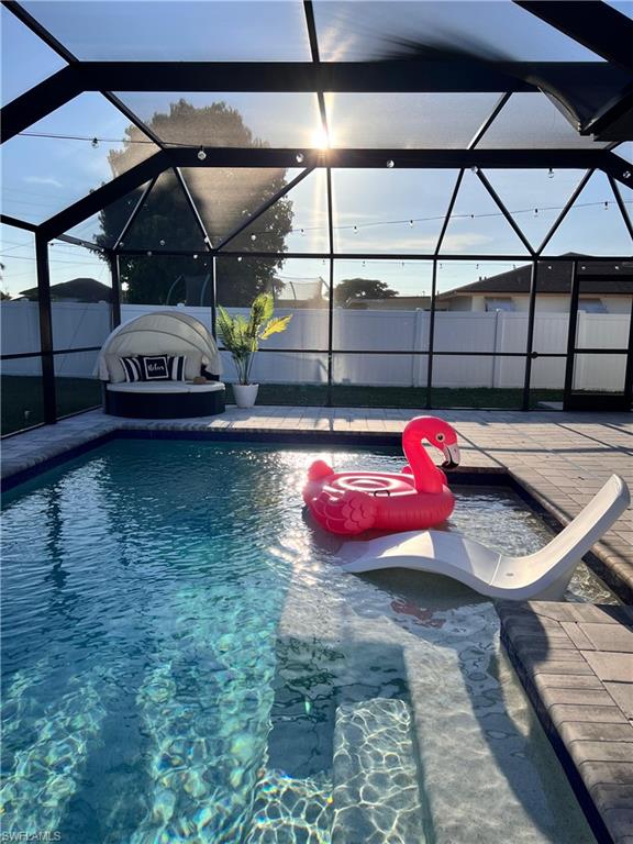 Screened pool enclosure featuring a sun shelf, integrated steps, and paver decking