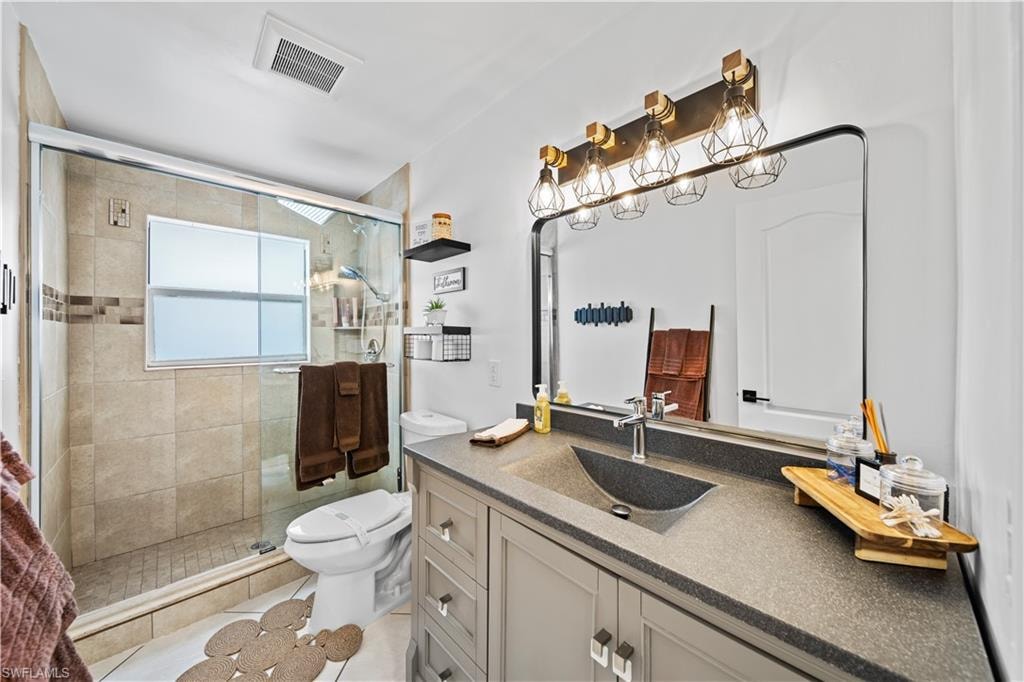 Modern bathroom featuring a glass-enclosed shower with tile surround, a built-in window, and a gray vanity with an integrated sink
